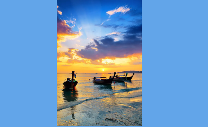 Sunset view over Patong Beach with traditional longtail boats silhouetted against golden skies